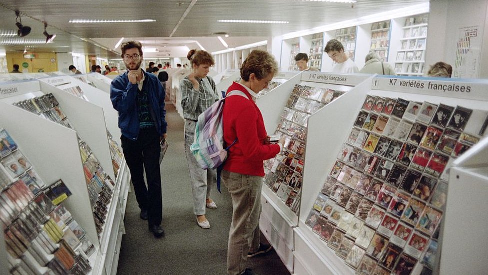 Customers look at music cassettes displayed at a Fnac store, on August 28, 1987