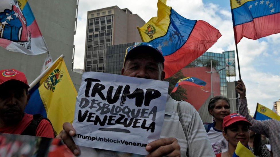 Проправительственный протестующий протестует против санкций США с табличкой «Трамп разблокирует Венесуэлу» в Каракасе 7 августа 2019 г.