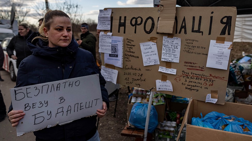 Una mujer con un cartel en la frontera con Hungría