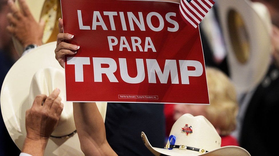 Una mujer sujeta un aviso que dice Latinos para Trump.