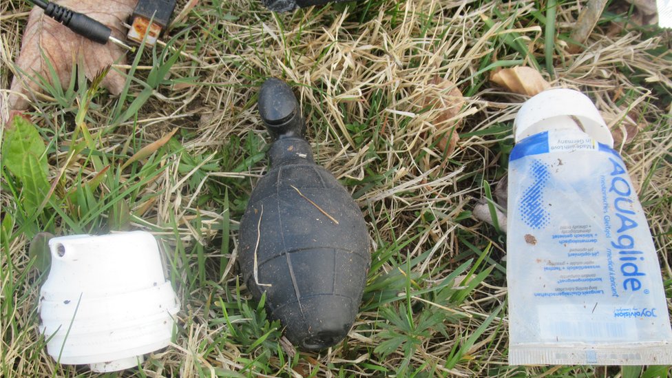 A grenade-shaped object is seen next to a tube of lubricant and a USB cord in place handout image
