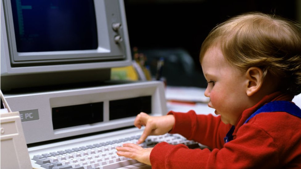 Un niño juega con un antiguo computador