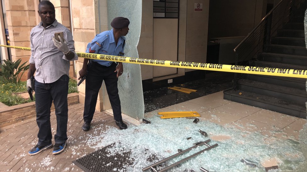 Armed plain clothes officials secure the damaged entrance of a hotel in Nairobi, Kenya