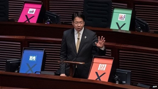 Представитель Гонконга, выступающий за демократию, Чарльз Мок обращается к законодательному собранию города рядом с плакатами, символизирующими голосование против неоднозначного правительственного плана действий по выборам в Гонконге 18 июня 2015 г.