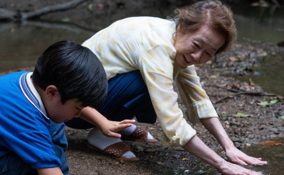Una escena de Minari en donde aparecen plantando la tierra Soonja, el personaje de la abuela, junto a su pequeño nieto, David.