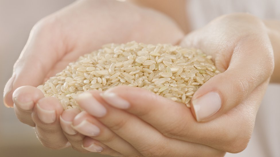Woman holding handful of brown rice.