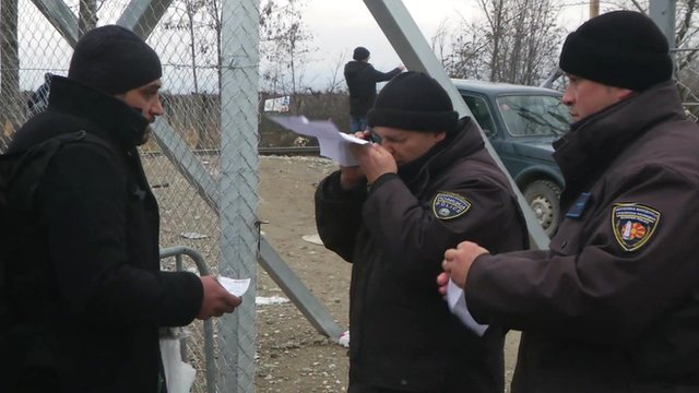 Border official check migrant's papers at Greece Macedonia border