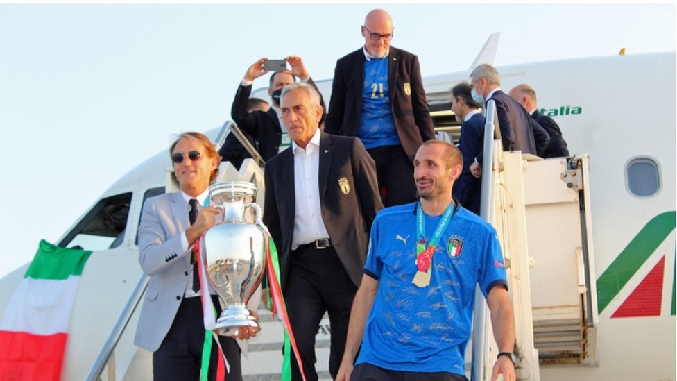 Italy captain Giorgio Chiellini (R) and head coach Roberto Mancini (L) hold the trophy after the team's plane landed