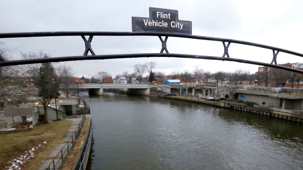 На фото из файла видна вывеска над рекой Флинт, на которой Флинт, штат Мичиган, обозначен как Транспортный город.
