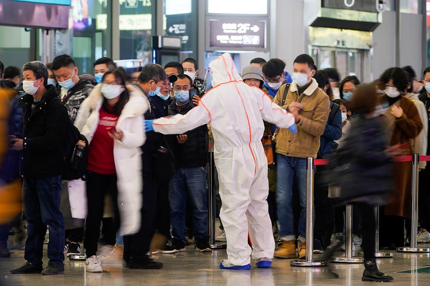 上海虹橋火車站一名安檢員指示人們掃描健康碼。