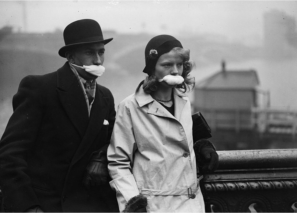 Pedestres em uma rua de Londres usando máscaras na boca