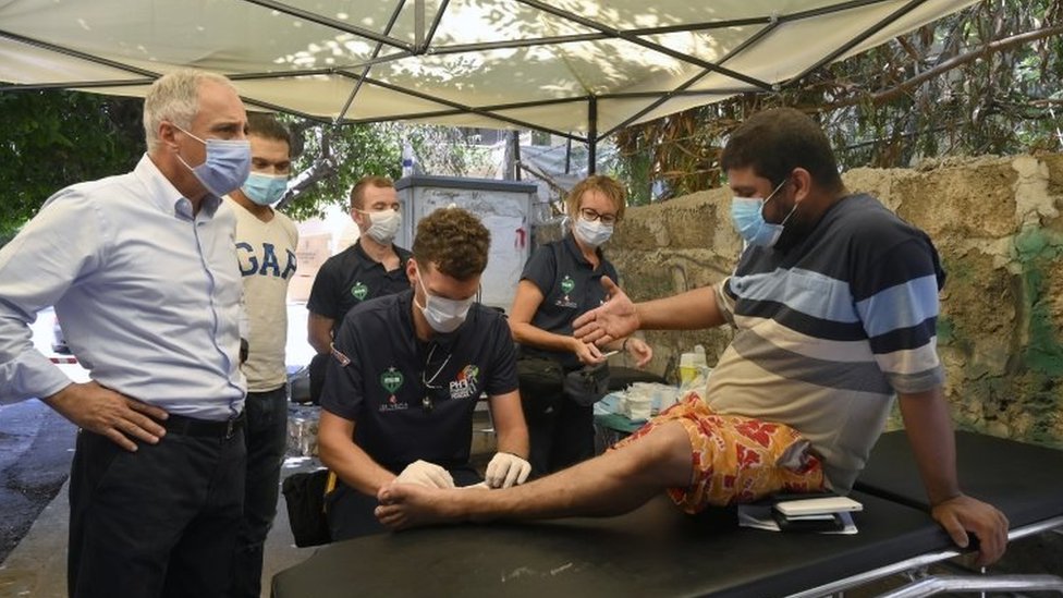 Французский врач из Pompiers Humanitaires Francais (PHF) лечит мужчину перед больницей Wardieh на улице Геммайзе в Бейруте, Ливан (11 августа 2020 г.)