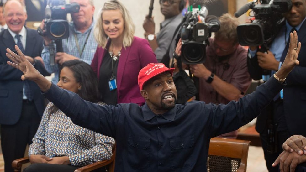 Kanye West con una gorra de Make America Great Again y rodeado de periodistas.