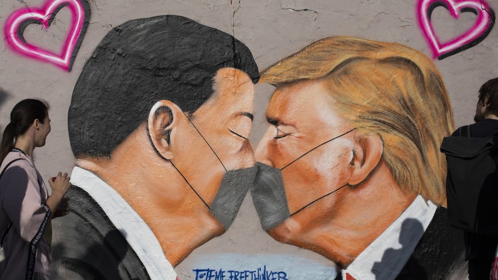 Стрит-арт показывает, что президент США Дональд Трамп и президент Китая Си Цзиньпин целуются в защитной маске и целуются на участке бывшей Берлинской стены.