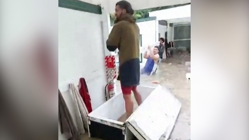 Cyclone Gabrielle: Workers use fridge and mattress to navigate floods