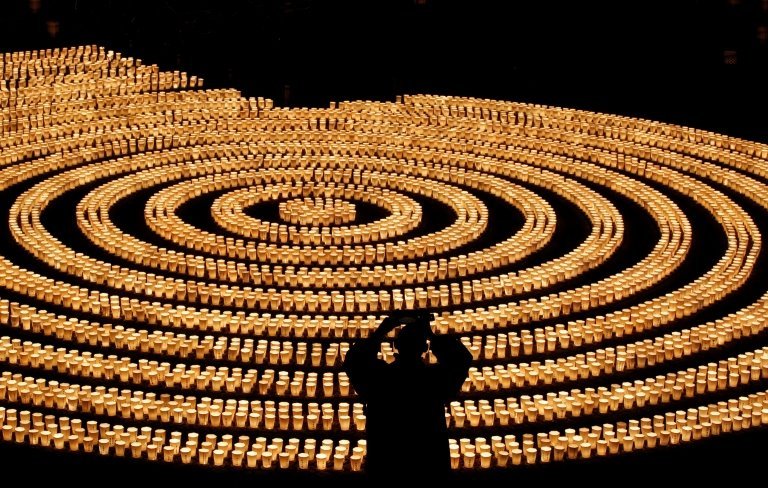 New Year eve celebrations in Japan 31/12/2021 Reuters A staff wearing a protective mask, amid the coronavirus disease (COVID-19) outbreak, takes picture of 6,500 candle lights as he prepares for a ceremony to wish for overcoming the pandemic and good luck in the upcoming New Year at Hasedera Buddhist temple in Kamakura, south of Tokyo, Japan, December 31, 2021. REUTERS/Kim Kyung-Hoon