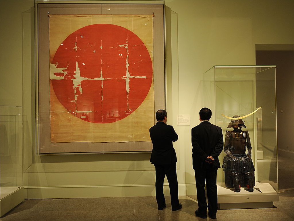 Bandeira histórica japonesa do siglo XVI ao lado de um samurai da armadura na exibição 