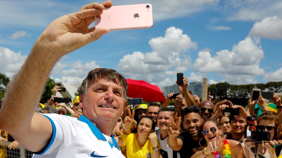 Президент Бразилии Жаир Болсонару делает селфи со сторонниками перед дворцом Планалто