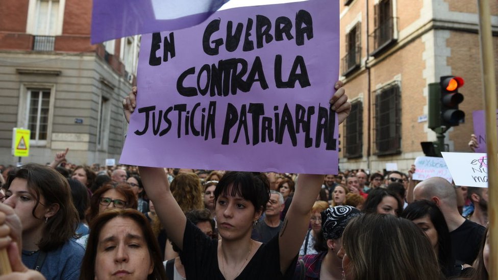 Женщина держит табличку с надписью «В войне против патриархальной справедливости»