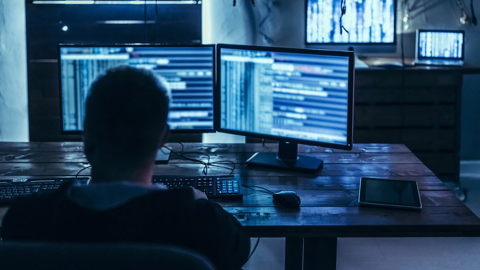 Homem em frente a diversos computadores