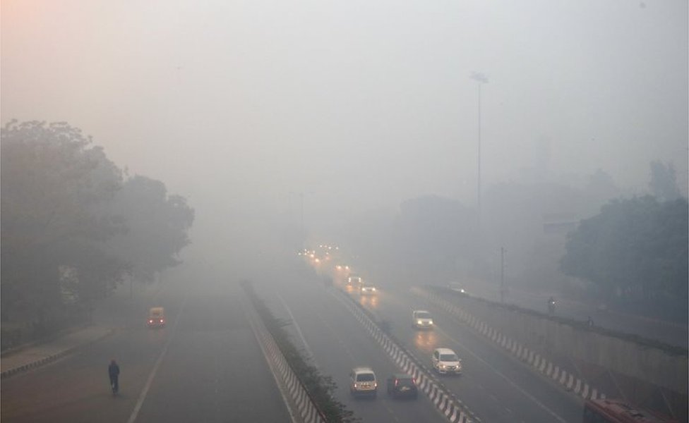 Движение транспорта по дороге, окутанной дымом и смогом, утром после фестиваля Дивали в Нью-Дели, Индия, в понедельник, 31 октября 2016 г.