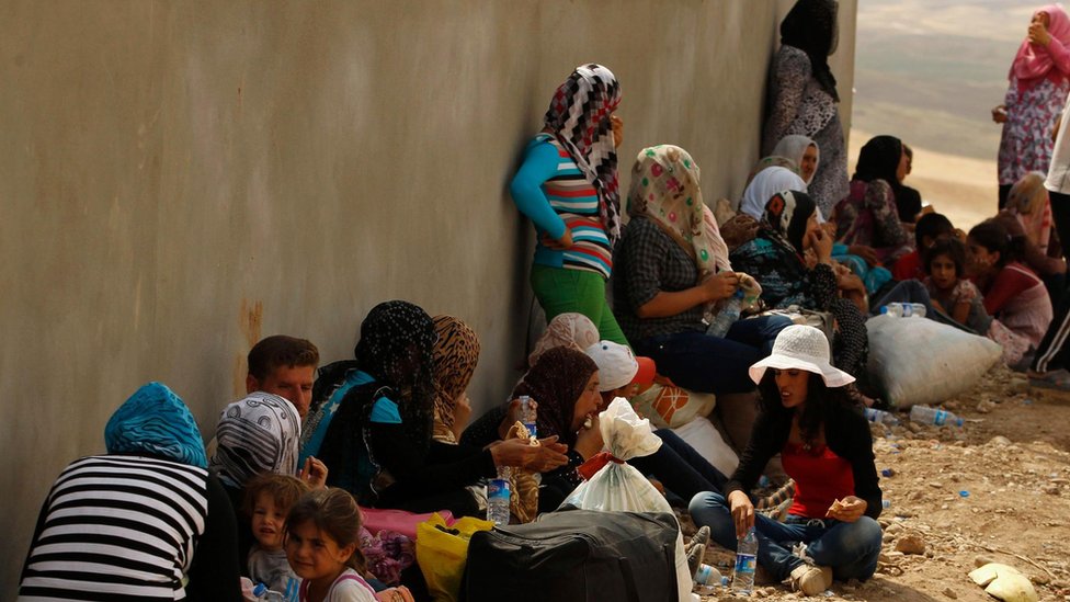 مجموعة من النساء والأطفال يجلسون في انتظار الخدمات الأساسية