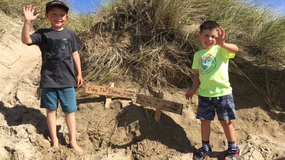 Флинн, 7 лет, и Тедди, 4 года, с табличками в песчаных дюнах