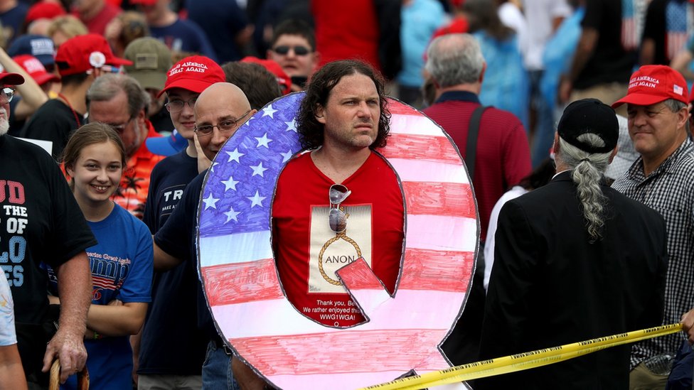 Un hombre con un cartel de Q