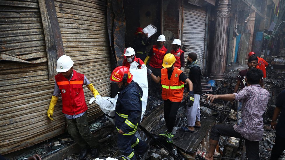 Volunteers recover a dead body from a burnt warehouse in Dhaka