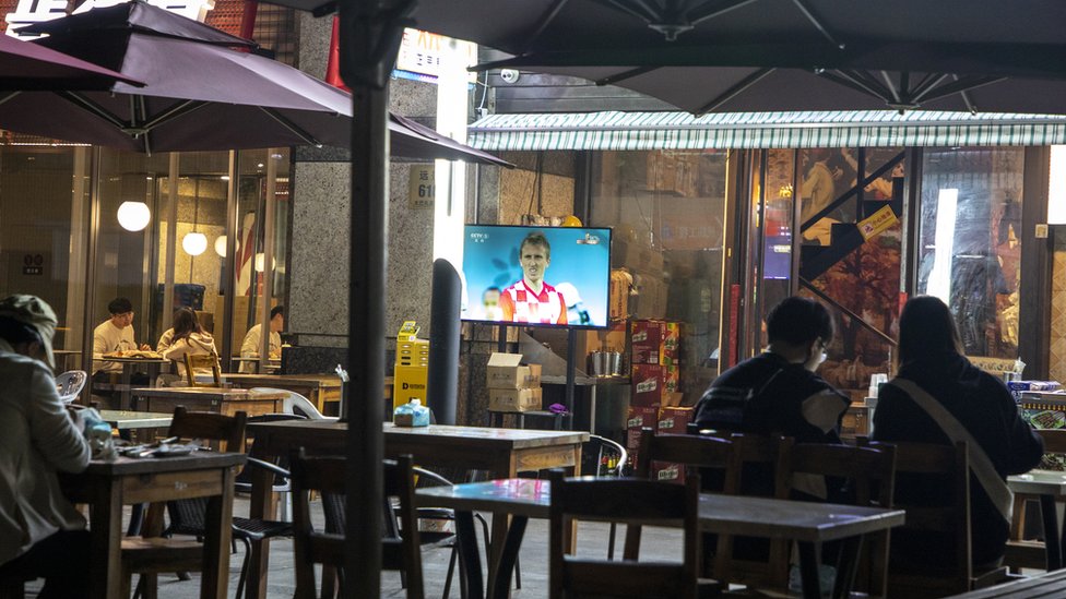 上海市民坐在幾乎空無一人的酒吧裏，看著克羅地亞足球運動員盧卡莫德里奇的屏幕