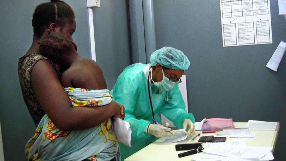 Mujer de Angola lleva a su hijo a una revisión durante un brote del virus de Marburgo en 2005 en Angola.