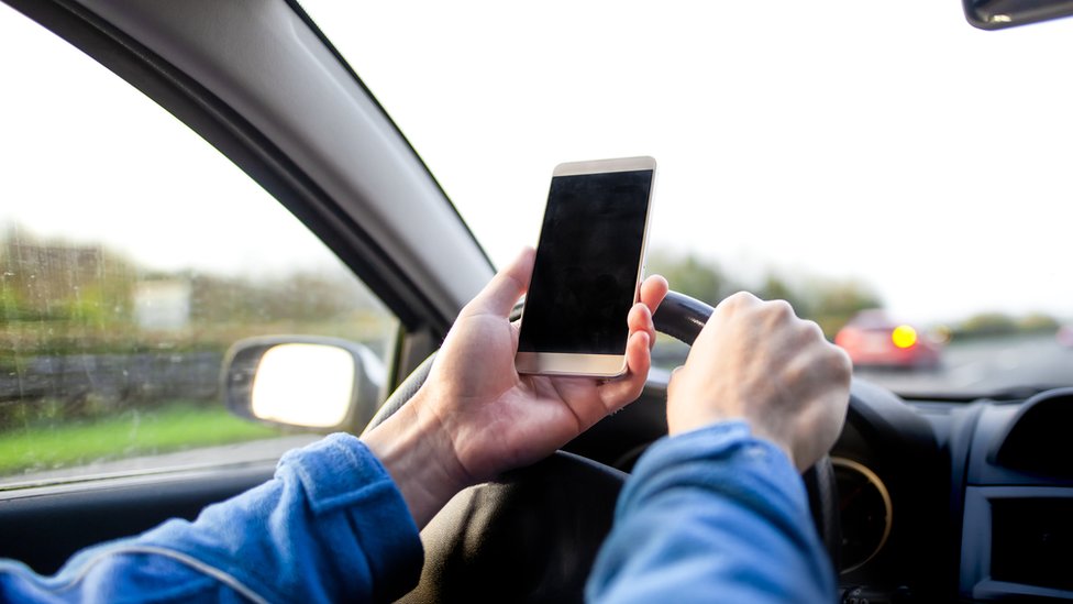 Una persona al volante con un celular