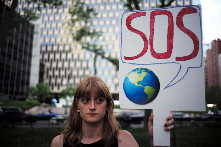 Numerosas protestas se desarrollaron en Estados Unidos este jueves tras el anuncio de Donald Trump. Una mujer sostiene un cartel con el planeta tierra diciendo SOS.