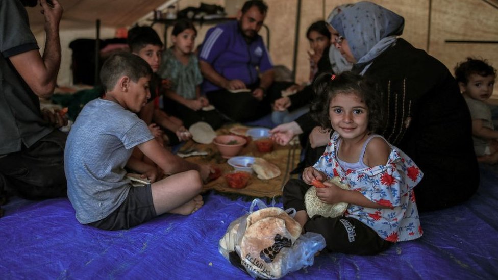 A Palestinian family sits inside a tent, enjoying lunch in a refugee camp in Khan Yunis on October 20, 2023.