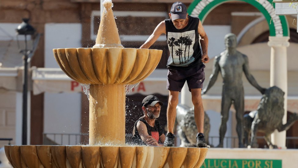 Men cooling off in a fountain in Ronda, Spain, 10 July 2022