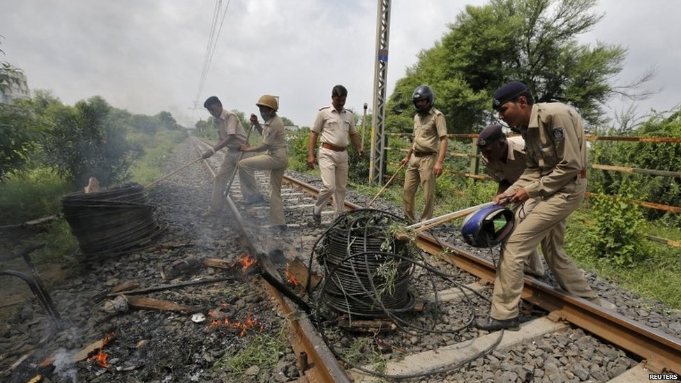 Полицейские снимают кабели с железнодорожного полотна, подожженного протестующими в Ахмедабаде, Индия, 26 августа 2015 года.