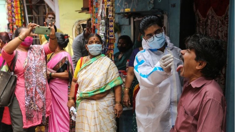 A health worker in personal protective equipment (PPE) collects a swab sample from a man during a testing campaign for the coronavirus disease (COVID-19), at a slum area in Mumbai, India, March 18, 2021.
