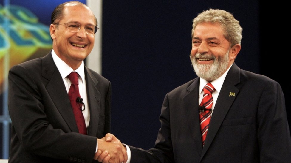 Alckmin e Lula sorriem enquanto apertam a mão