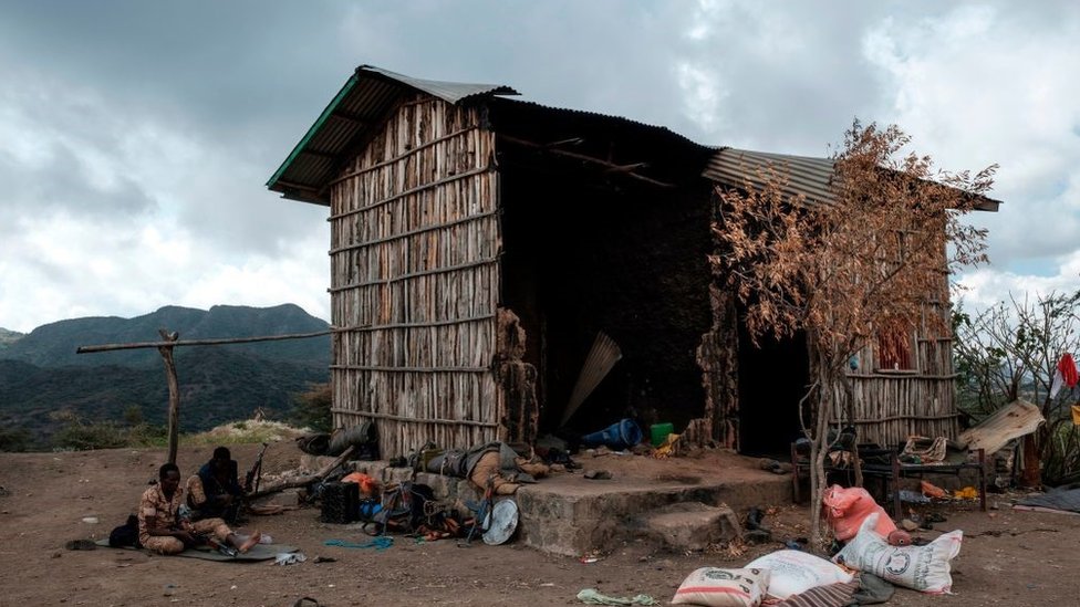 Members of the Afar Special Forces sit next to a damaged house in the outskirts of the village of Bisober, Tigray Region