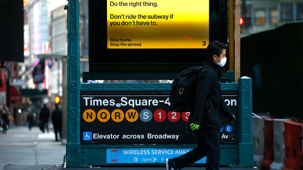 Мужчина проходит мимо станции метро Times Square на 42-й улице, когда Нью-Йорк пытается замедлить распространение коронавируса с помощью социального дистанцирования 1 апреля 2020 г.