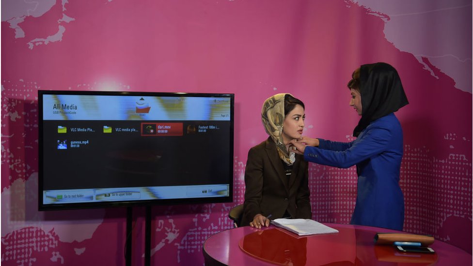 Seorang perempuan Afghanistan merapikan kerudung presenter berita sebelum rekaman di stasiun televisi Zan TV di Kabul pada Mei 2017.