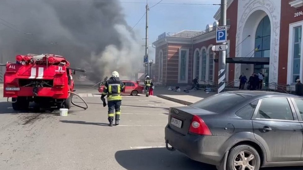 Firefighters attend to a fire after a bombing at a train station in Donbas