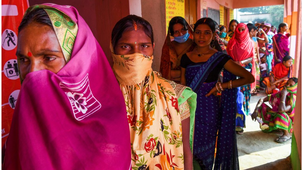 Indian women queue to vote at a polling station