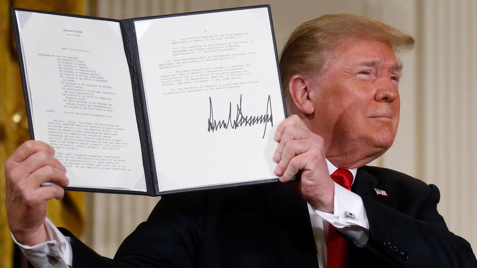 US President Donald Trump displays his signature after signing a national space policy directive during a meeting of the National Space Council