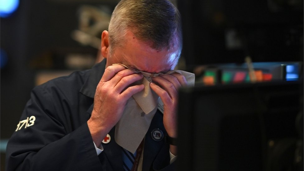 A trader wipes his brow on the NYSE floor