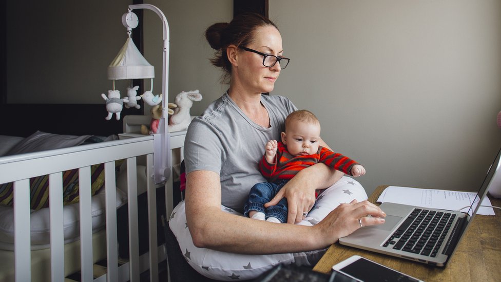 Женщина перед компьютером с младенцем на коленях
