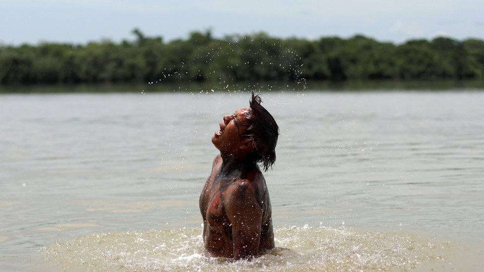 Коренной житель племени куикуру принимает ванну на реке Шингу