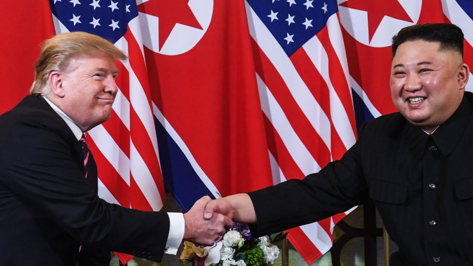 Президент США Дональд Трамп (слева) пожимает руку лидеру Северной Кореи Ким Чен Ыну