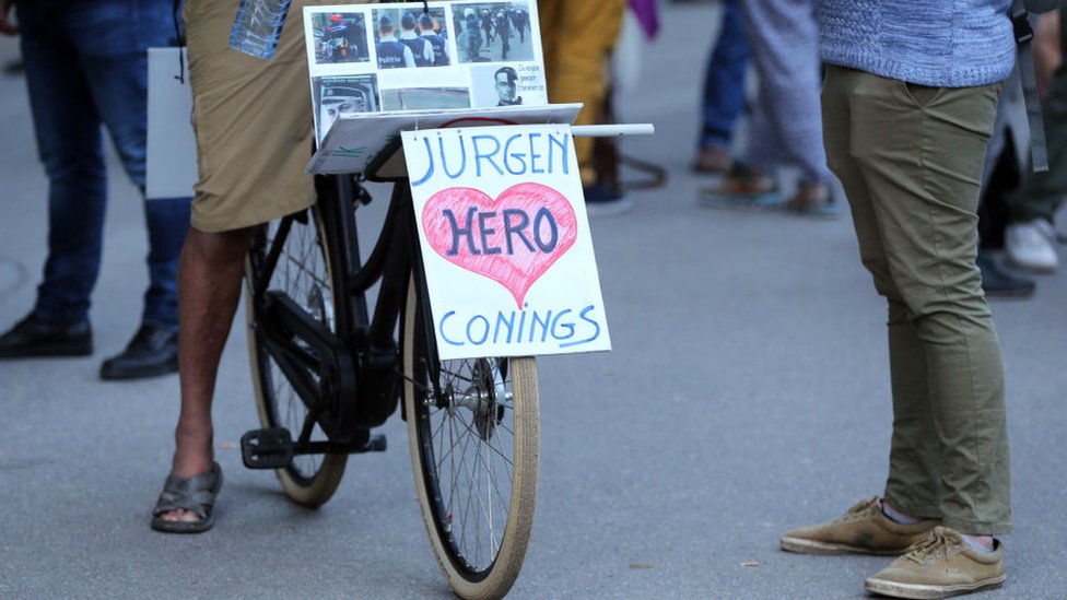 Um ciclista anda de bicicleta com uma faixa em apoio ao soldado belga de extrema direita Jürgen Conings em 29 de maio