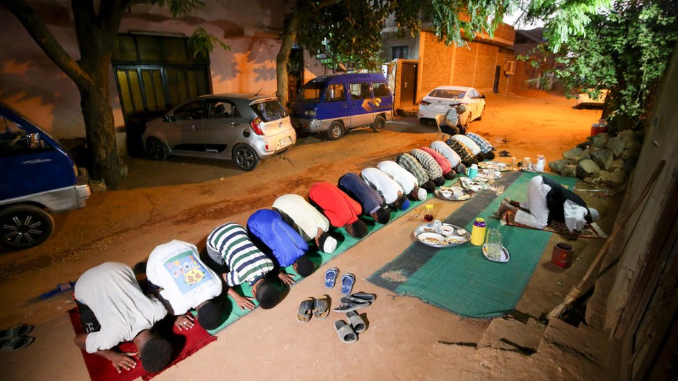 Суданские мужчины собираются на молитву на улице в столице Хартуме после того, как они прервали пост во время священного для мусульман месяца Рамадан 25 апреля 2020 года, на фоне комендантского часа из-за пандемии коронавируса COVID-19.